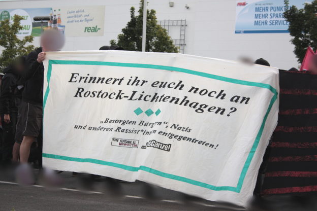 Transparent: "Erinnert ihr euch noch an Rostock-Lichtenhagen? "Besorgten Bürgern", Nazis und anderen Rassist*innen entgegen treten. the future is unwritten. um's Ganze"